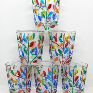 A set of 6 glass shot glasses, stacked in a pyramid. Each shot glass features a multicolored branch and petal design.