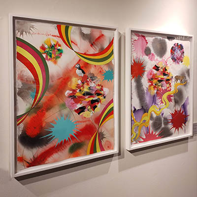 There are two abstract artworks by Kara Maria. Each artwork features several splashes of colors with a dominance of red. The artwork on the left includes some green lines and splashes of marine blue, while the artwork on the right features yellow lines and splashes of grey