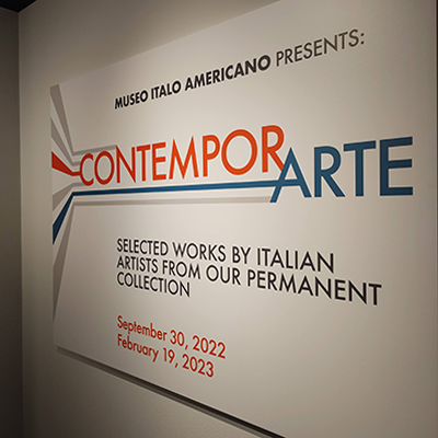 An image of the title wall panel with the title of the exhibit "ContemporArte" written on two lines. The word "Contempor" is in orange and on the top line, and the word "Arte" in blue on the lower line. Below the title, another line with the text "Selected works by Italian Artists from Our Permanent Collection