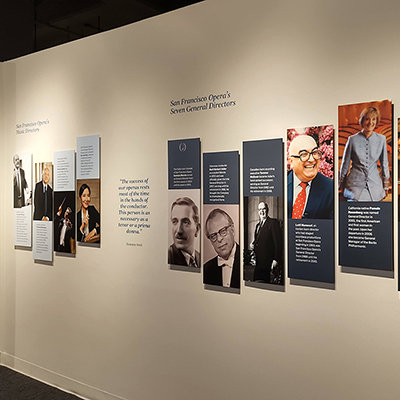 A wall with several panels showing the four San Francisco Opera managing directors and the seven San Francisco Opera general directors. Each panel features an image of the person along with a short bio.