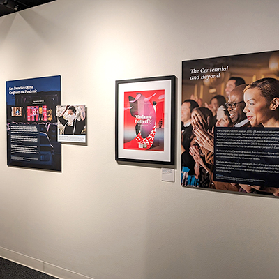 This is the final wall of the exhibition, featuring a panel dedicated to the pandemic and how the opera managed the Covid-19 crisis, and another celebrating the centennial. Between these two large panels, there is an image of a person wearing a special mask created for opera singers, along with a poster of Madame Butterfly