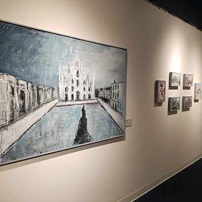 The wall has a painting of Milan's Duomo on the left side. On the right side, there are six small paintings.