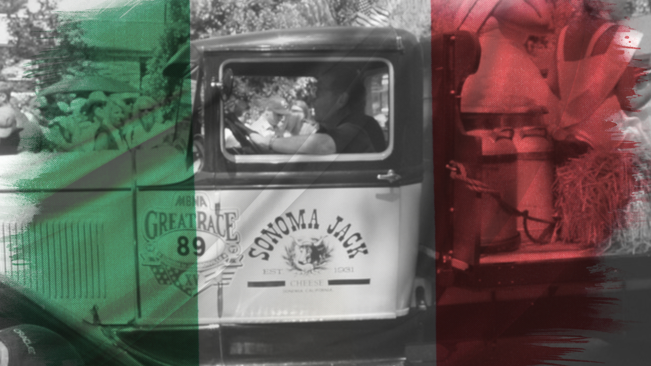 An image of an old truck with a man driving it. Over the image is a translucent Italian flag.