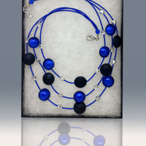 A three-tiered necklace featuring blue and black beads of handblown glass.