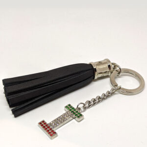 A silver keychain with a black pleather tassel and a capital "I' bedazzled with the colors of the Italian flag.