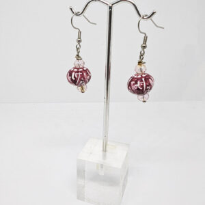 A pair of dangle earrings with a glass bead painted with maroon swirling patterns, on silver hooks accented with small clear beads.