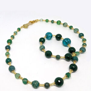 A string necklace with green-hued glass beads with gold spacer beads.