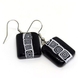A pair of glass dangle earrings, featuring a black and white abstract square pattern down the center.
