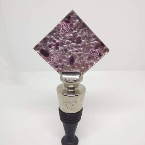 A square-shaped, glass wine stopper with a plum and cream wave design, featuring a few small millefiori flowers.