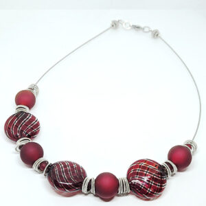 A necklace with deep red glass beads and silver spacer rings on a metal cord.