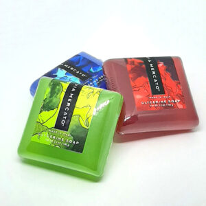 Three square-shaped soaps in green, red, and blue with packaging featuring an abstract design and VIA MERCATO logo.