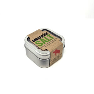 A small, metallic tin of salt, wrapped in a brown paper sleeve with "OMNIVORE SALT".
