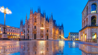 Photograph of an Italian plaza at sunset, facing a gothic style church.