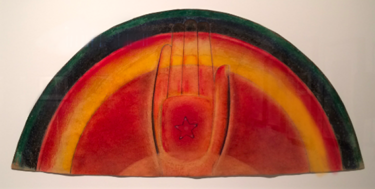 A pastel drawing on wove paper depicting a rainbow-shaped form with a hand of peace in the center. The hand, solely an outline, emerges from the rainbow, with shading on each side. Within the center of the palm is a small star, outlined in black. The colors range from green, to dark blue, to black, to red, to yellow, to red, to orange, all blended in the shape of a rainbow.