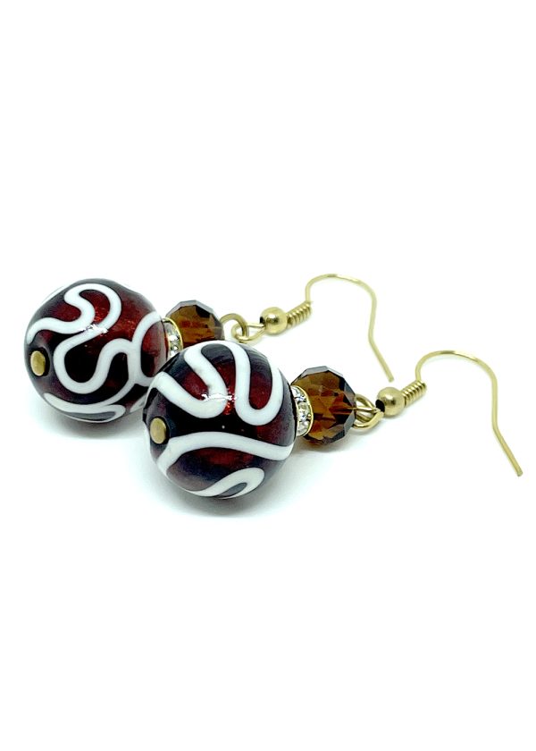 Calliope is a unique pair of earrings, with an an overlay of raised white glass in a swirl pattern, topped off with a bright red glass bead.