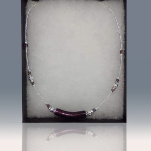 A necklace with a unique detail in the central deep violet blown glass pendant, featuring delicate sequences of deep violet and silver-colored beads around the rest of the necklace.