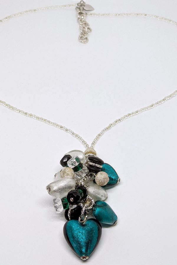 White and peacock-colored hearts are combined with green, silver, black, and transparent beads to create a unique focal point in this gorgeous necklace. The pendant and delicate beading throughout add to its charm.