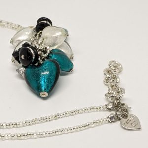 White and peacock-colored hearts are combined with green, silver, black, and transparent beads to create a unique focal point in this gorgeous necklace. The pendant and delicate beading throughout add to its charm.